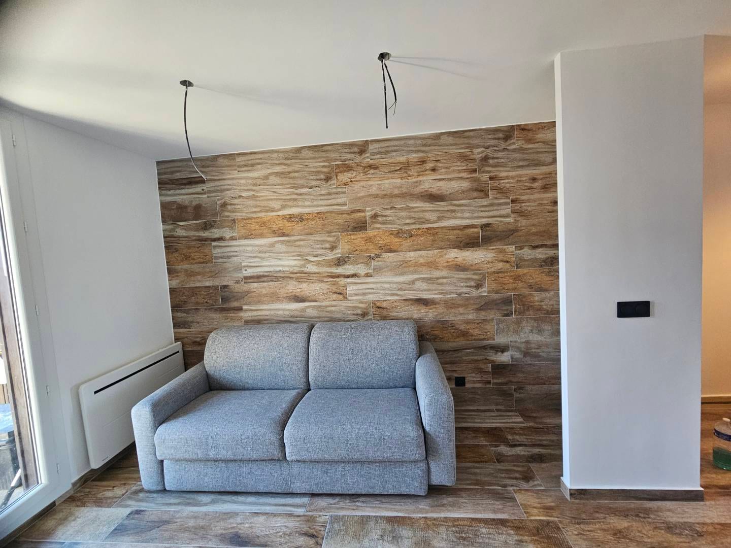 Mur en carrelage imitation bois dans un séjour, posé jusqu'au plafond