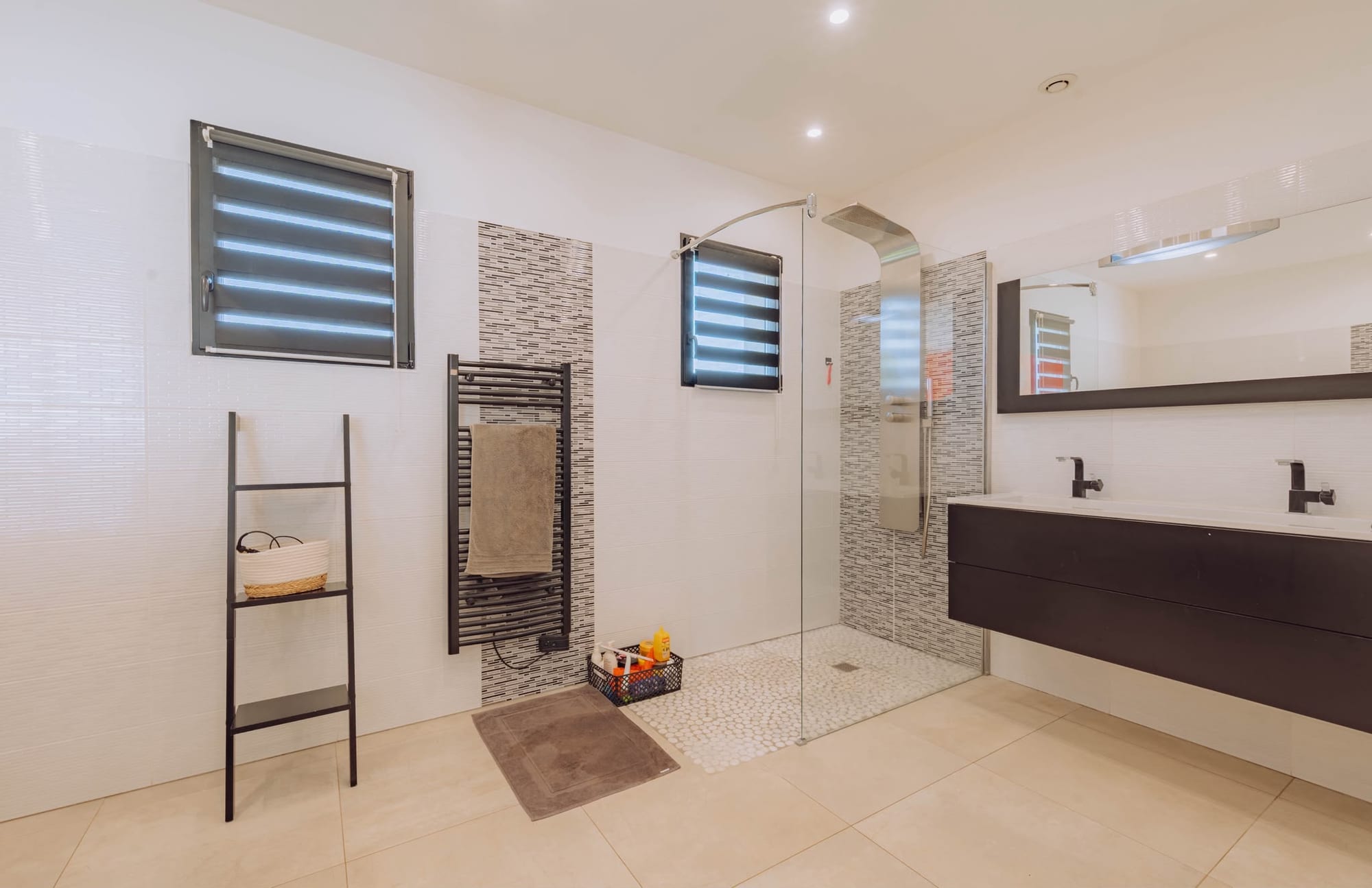 Salle de bain avec douche à l'italienne à fond de galets, double vasque et sèche-serviettes